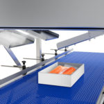 Förderband mit Styroporbox, die frischen Lachs enthält und unter einer Trockeneisscheibenproduktionsmaschine automatisch mit Trockeneis zur Lebensmittelkühlung befüllt wird.
